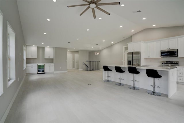 kitchen featuring white cabinetry, a large island, appliances with stainless steel finishes, and beverage cooler