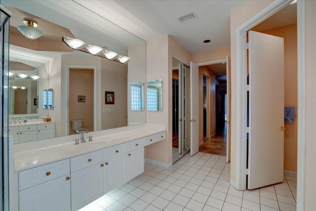 bathroom featuring a textured ceiling, tile patterned floors, vanity, and toilet