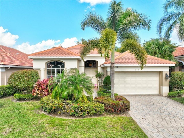 mediterranean / spanish-style house featuring a garage and a front lawn