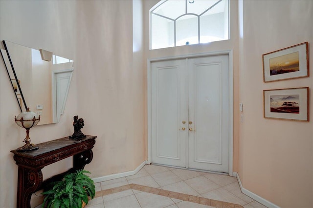 entryway with light tile patterned floors and a towering ceiling