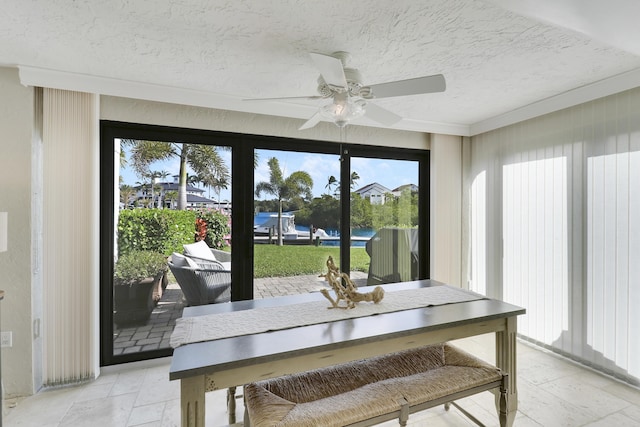 sunroom / solarium featuring ceiling fan and a water view