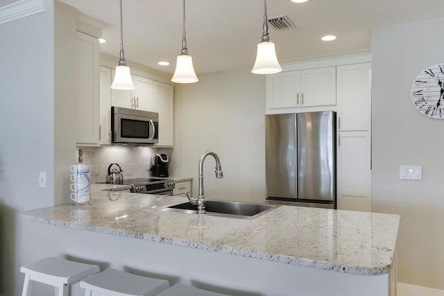 kitchen with stainless steel appliances, hanging light fixtures, kitchen peninsula, white cabinets, and sink