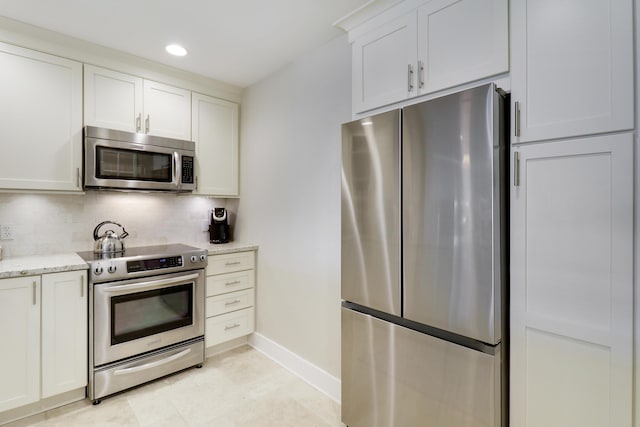 kitchen featuring stainless steel appliances, light stone countertops, white cabinets, and decorative backsplash