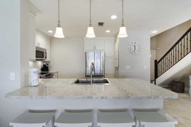 kitchen featuring kitchen peninsula, hanging light fixtures, stainless steel appliances, white cabinets, and sink