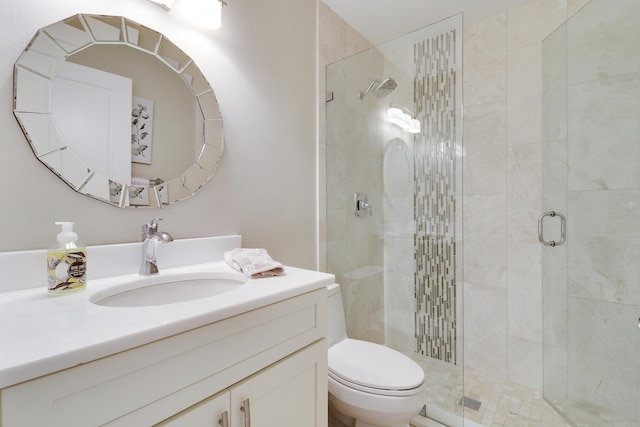 bathroom featuring toilet, a shower with shower door, and vanity