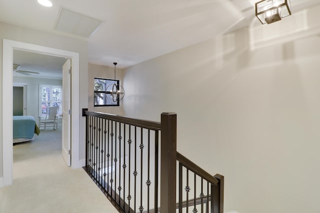 hallway featuring light colored carpet and a notable chandelier