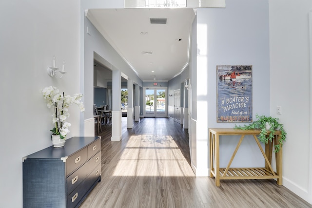 hallway featuring ornamental molding and light hardwood / wood-style flooring