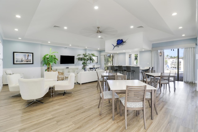 dining room with light hardwood / wood-style floors, ceiling fan, a raised ceiling, and plenty of natural light