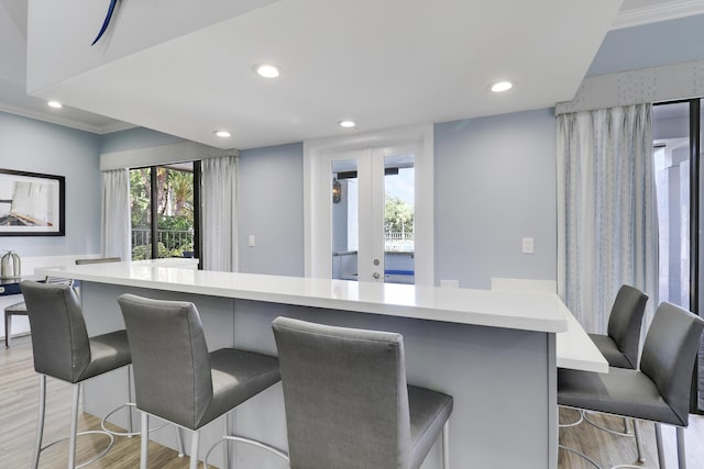 kitchen with a kitchen breakfast bar, ornamental molding, light hardwood / wood-style flooring, and a spacious island