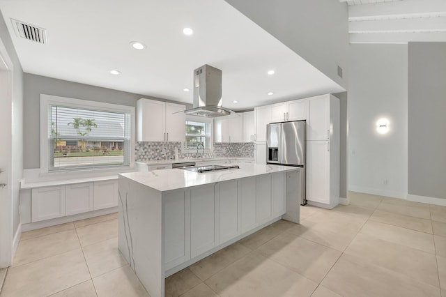 kitchen featuring white cabinets, light stone countertops, island range hood, and a center island