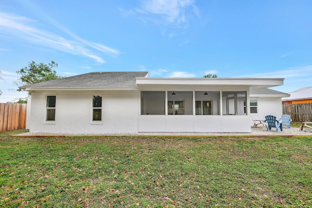 rear view of house featuring a sunroom and a yard