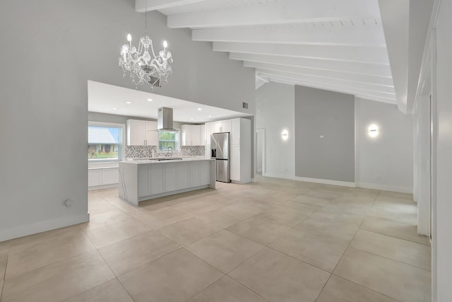 kitchen featuring decorative light fixtures, vaulted ceiling with beams, decorative backsplash, island exhaust hood, and stainless steel fridge