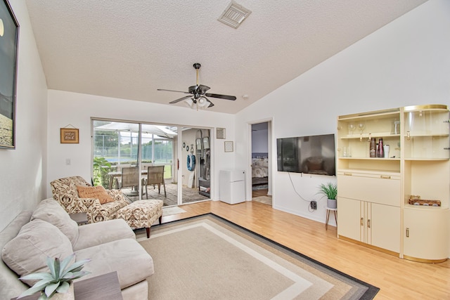 living room featuring wood-type flooring, a textured ceiling, lofted ceiling, and ceiling fan