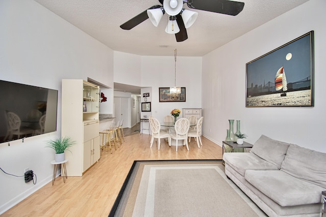 living room with ceiling fan with notable chandelier, hardwood / wood-style floors, and a textured ceiling