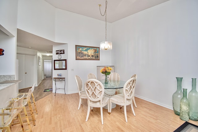 dining space with a high ceiling, a chandelier, and light wood-type flooring