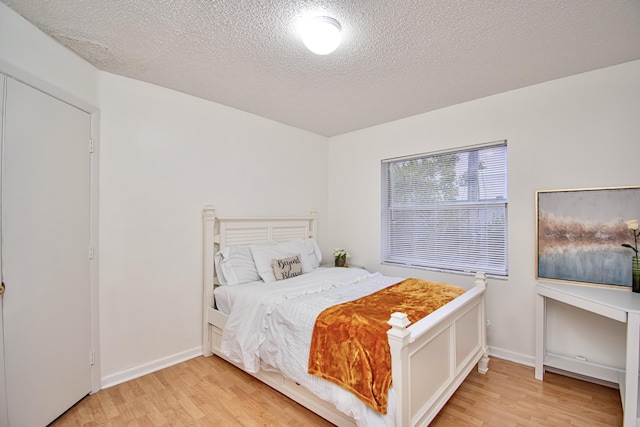 bedroom with light hardwood / wood-style floors and a textured ceiling