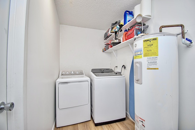 laundry room with washer and clothes dryer, light hardwood / wood-style floors, a textured ceiling, and electric water heater