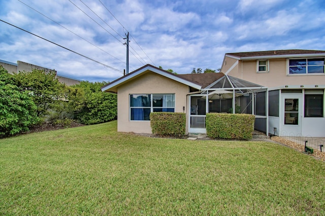 back of property featuring glass enclosure and a lawn