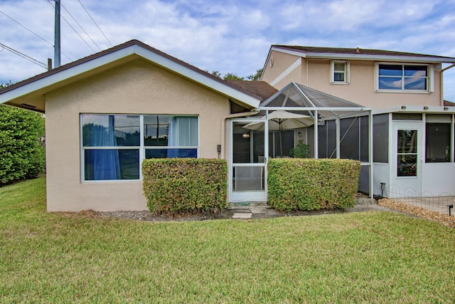 rear view of property featuring a lanai and a yard