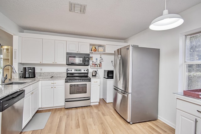 kitchen with appliances with stainless steel finishes, a textured ceiling, white cabinetry, sink, and decorative light fixtures