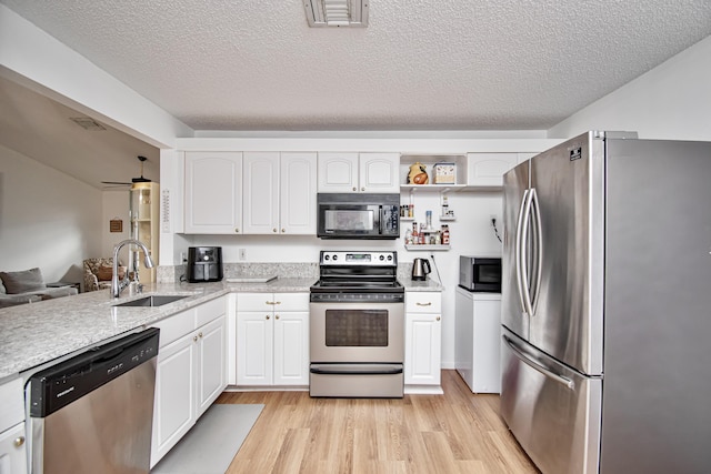 kitchen featuring white cabinets, light wood-type flooring, appliances with stainless steel finishes, and a textured ceiling