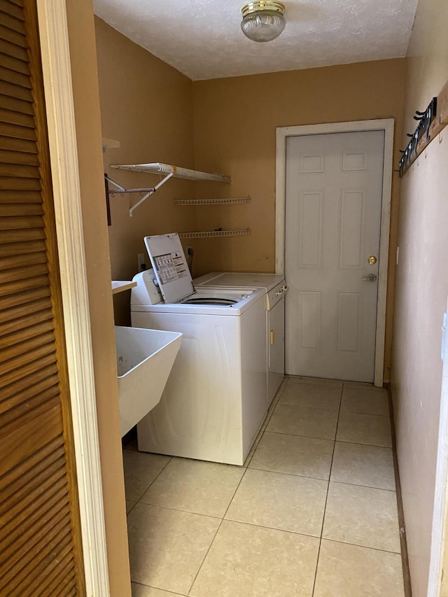 washroom with light tile patterned flooring, a textured ceiling, and separate washer and dryer