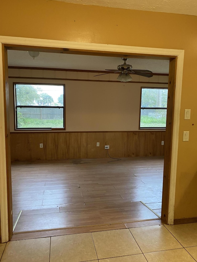 tiled empty room featuring ceiling fan and a healthy amount of sunlight