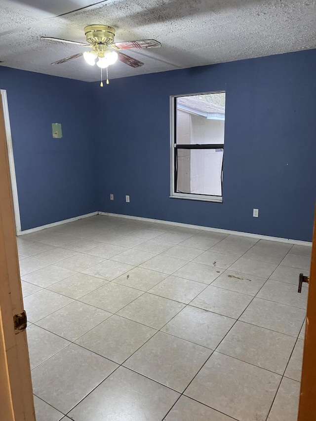 spare room with a textured ceiling, ceiling fan, and light tile patterned floors