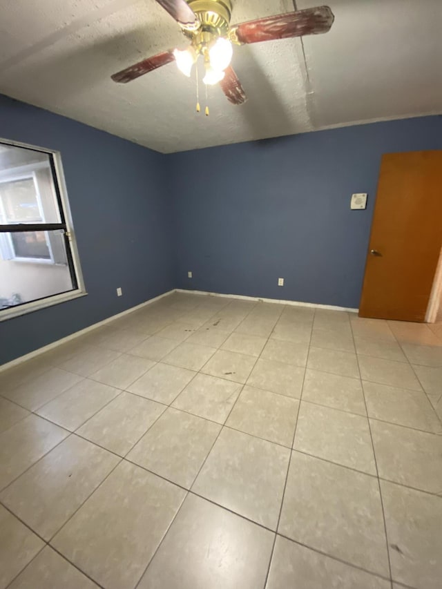 tiled spare room featuring a textured ceiling and ceiling fan