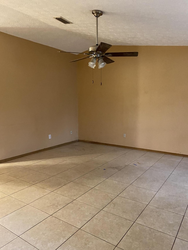 spare room with a textured ceiling, ceiling fan, and light tile patterned floors