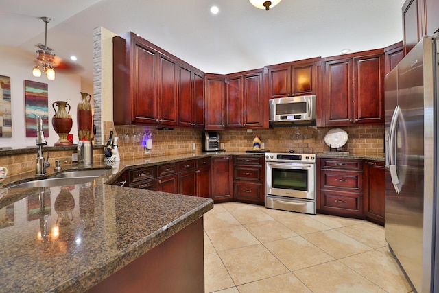 kitchen featuring vaulted ceiling, light tile patterned flooring, kitchen peninsula, pendant lighting, and appliances with stainless steel finishes