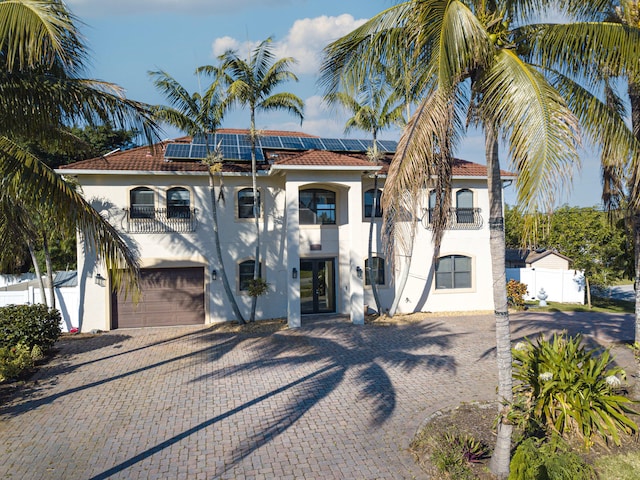 mediterranean / spanish house with a balcony, a garage, and solar panels