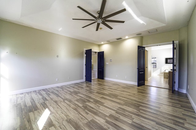 unfurnished room featuring a raised ceiling, ceiling fan, and hardwood / wood-style floors