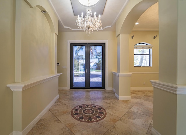 foyer with crown molding, french doors, an inviting chandelier, and a raised ceiling