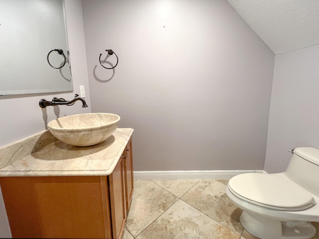 bathroom featuring toilet, tile patterned floors, vanity, a textured ceiling, and lofted ceiling