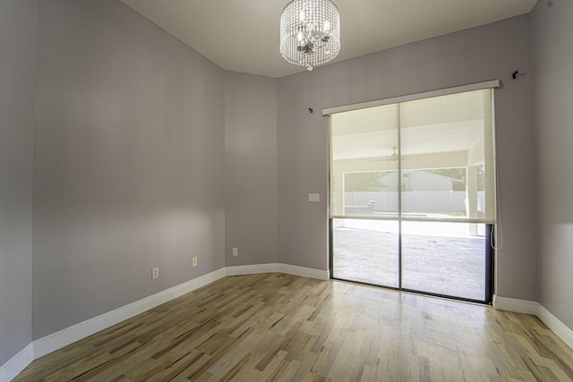 empty room with a notable chandelier and light hardwood / wood-style flooring