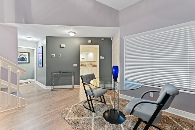 dining space featuring baseboards, a textured ceiling, and light wood-style floors