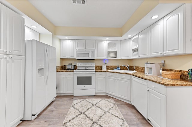 kitchen featuring white appliances, a sink, glass insert cabinets, and white cabinets