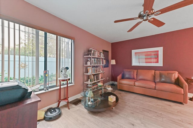 living room with light wood-type flooring, ceiling fan, and baseboards