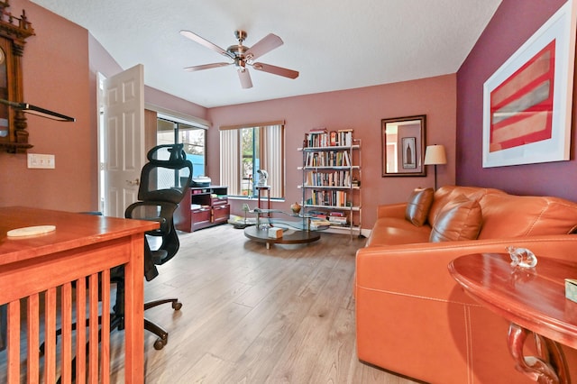 office space with light wood-type flooring, ceiling fan, a textured ceiling, and baseboards