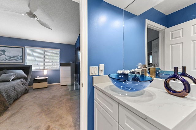 ensuite bathroom featuring a ceiling fan, connected bathroom, vanity, and a textured ceiling