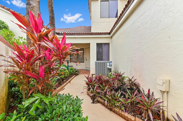 property entrance with a tile roof, fence, cooling unit, and stucco siding