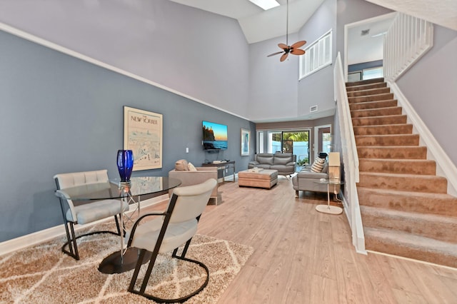 living area with light wood finished floors, stairway, a skylight, and baseboards