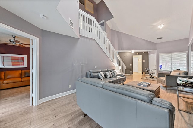 living room featuring ceiling fan, light wood-style flooring, visible vents, baseboards, and stairway