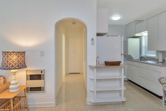 kitchen with sink, heating unit, and white cabinets