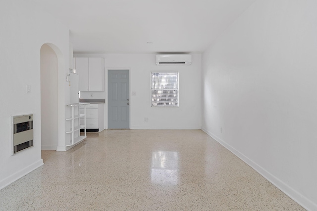 unfurnished living room featuring heating unit and a wall unit AC