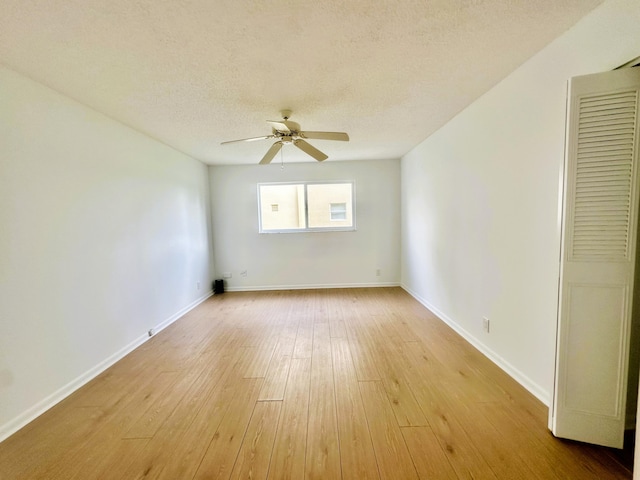 spare room with light wood-type flooring, baseboards, a textured ceiling, and a ceiling fan