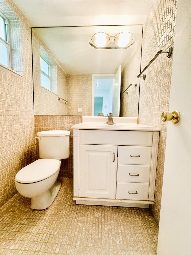 bathroom featuring toilet, tile walls, and vanity