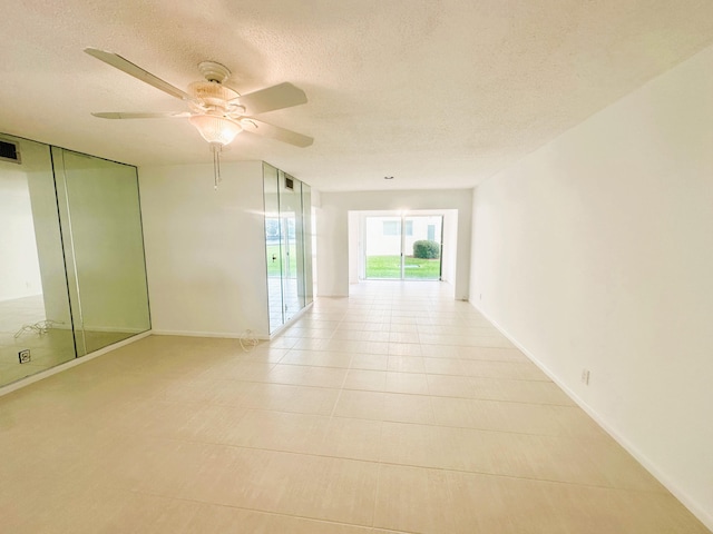 hall with a textured ceiling and light tile patterned floors