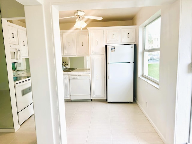 kitchen with light tile patterned floors, baseboards, white appliances, and white cabinets